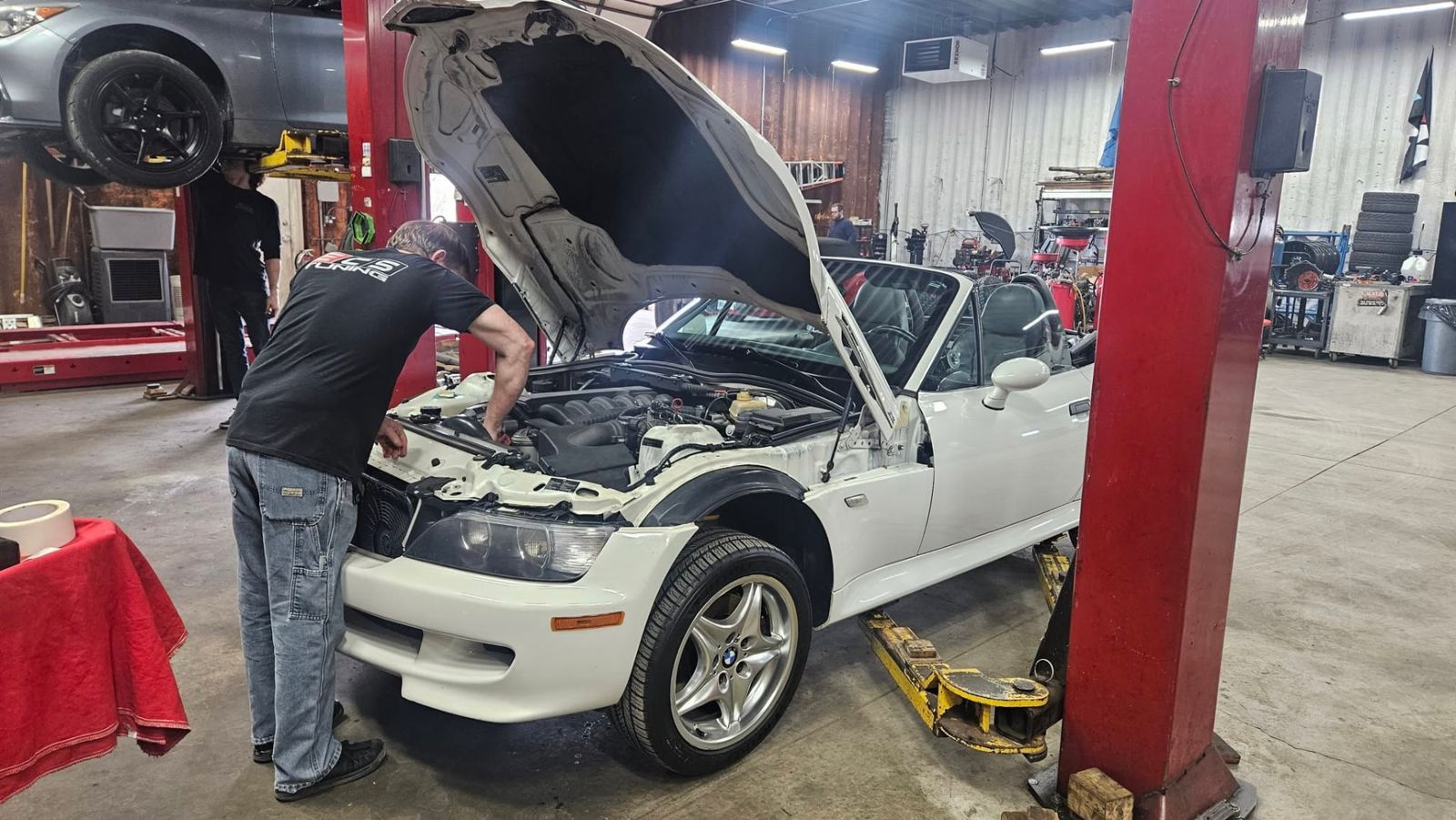 Technician servicing a white BMW Z3 M Roadster