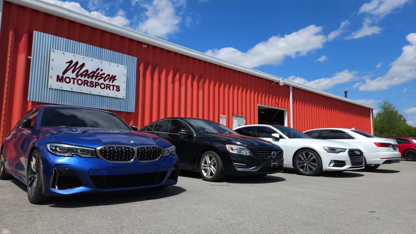 Blue BMW M340i and lineup in front of the shop sign
