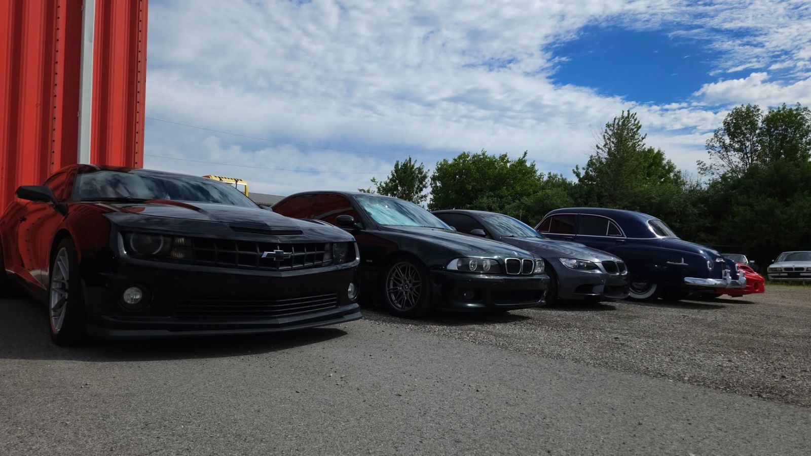 Camaro, BMW M5 and classic coupe lined up outside